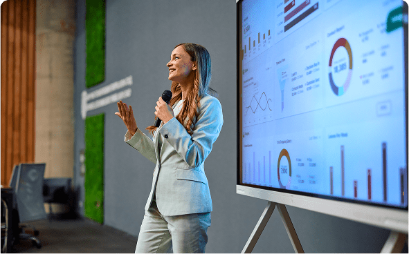 Woman presenting data on large screen.