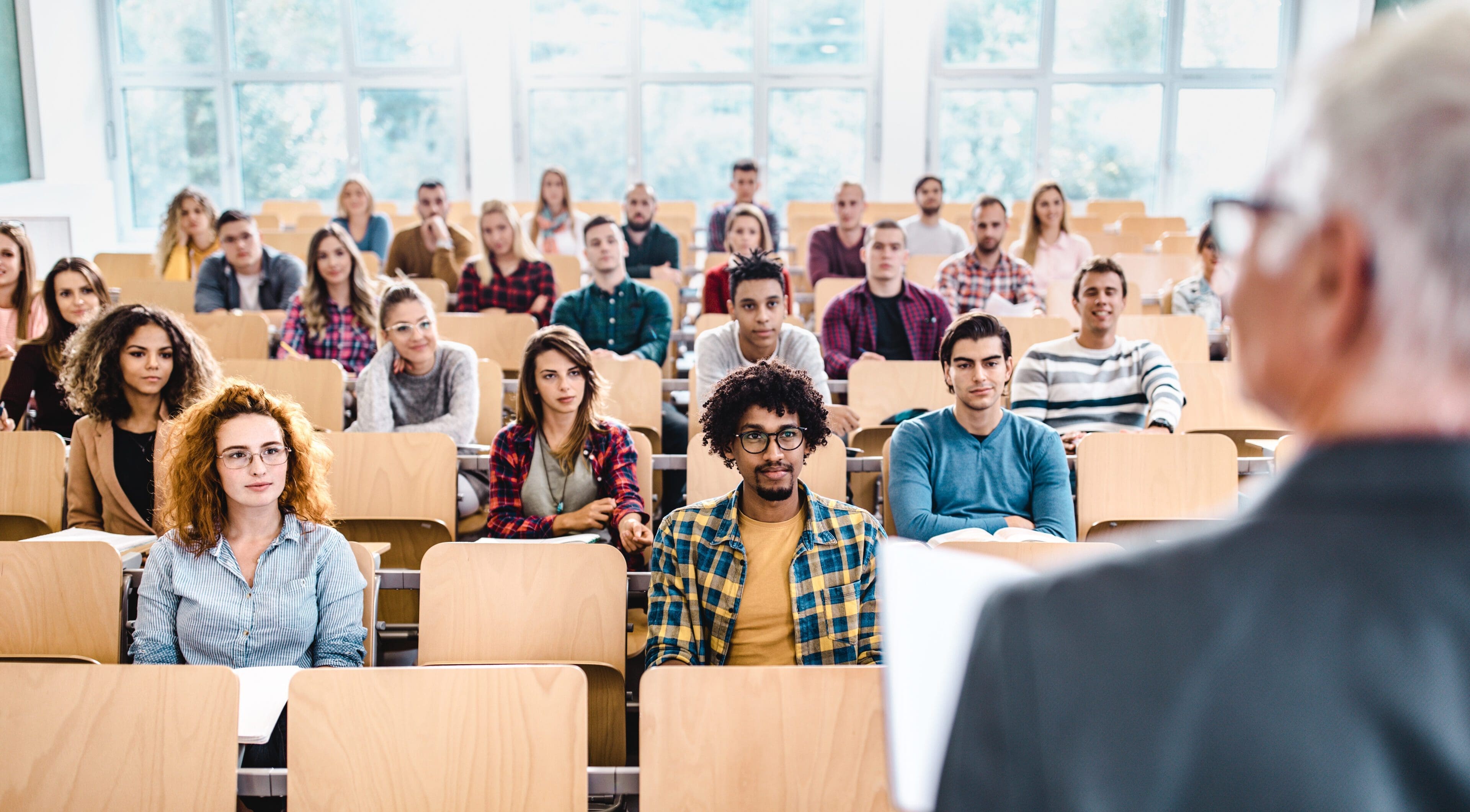 Students attentively listen to a lecture in a bright classroom.
