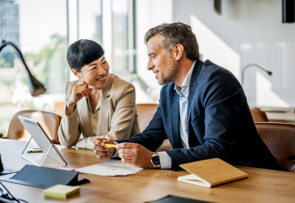 Two colleagues discussing work at a desk.
