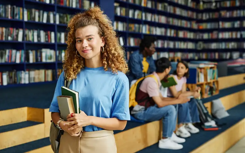 Student holding books in a library.